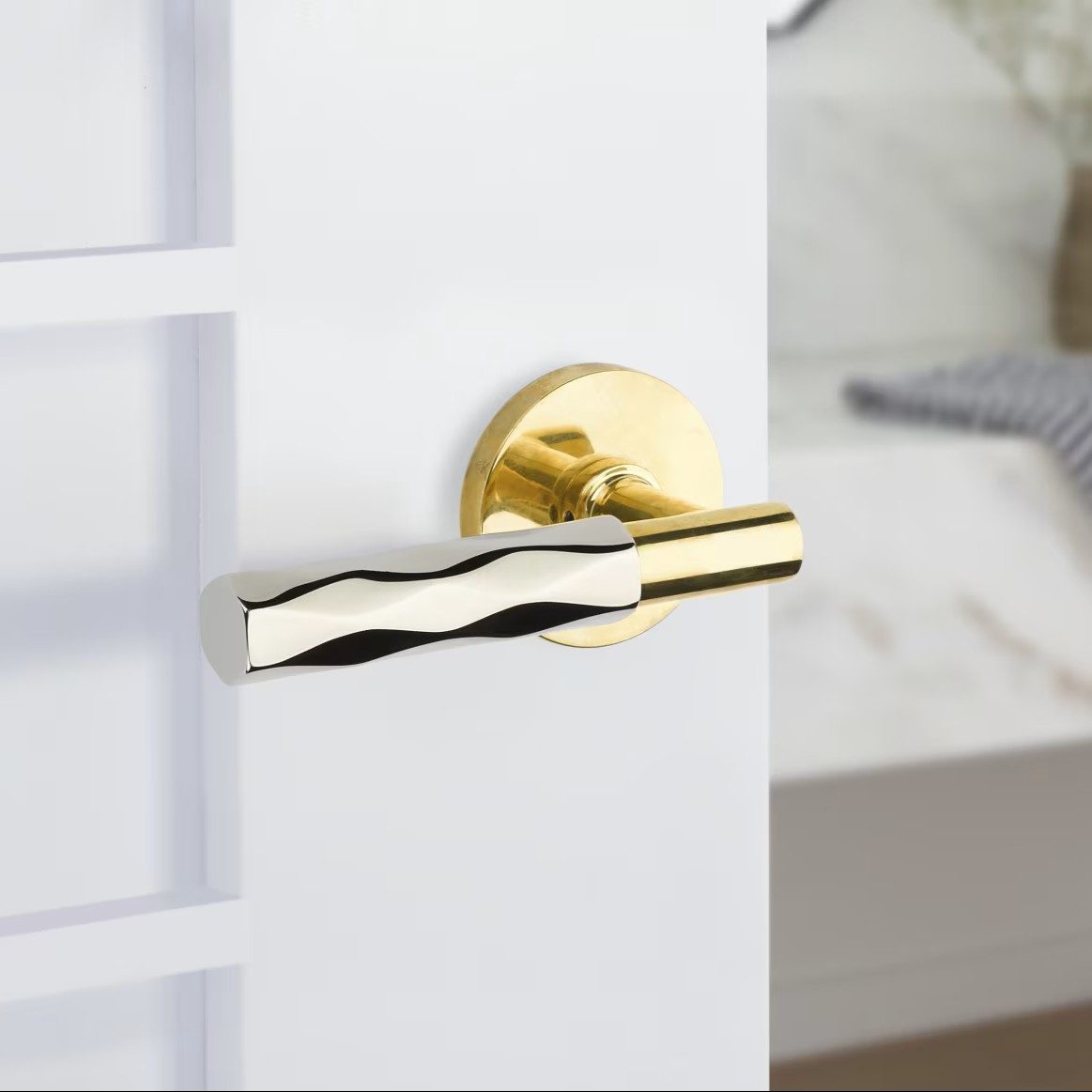 A satin brass lever handle on a white door, photographed close.