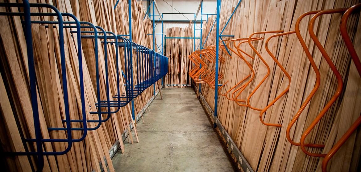 A long aisle of stacked moulding profiles in Fine Line's warehouse, blue and orange racking.