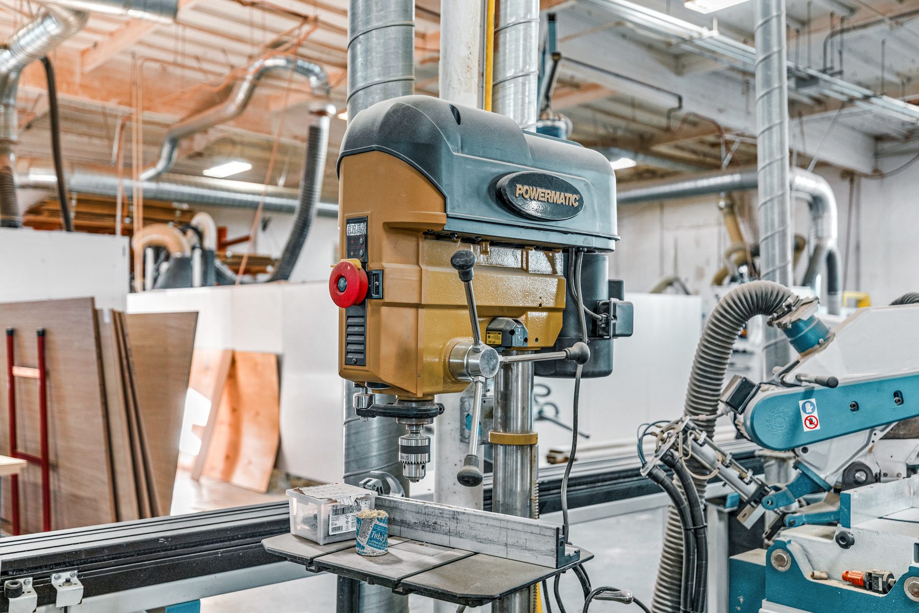A drill press station on Fine Line’s shop floor, dust extraction and machinery behind it.