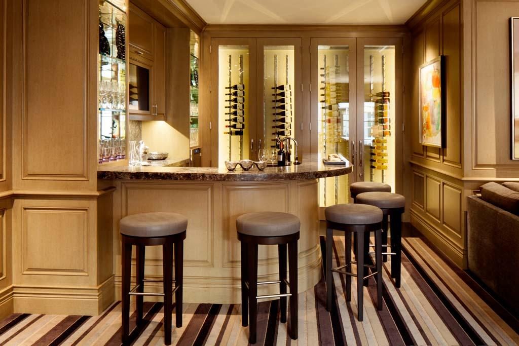 A panelled hardwood bar with stools and a lit back bar, built by Fine Line.