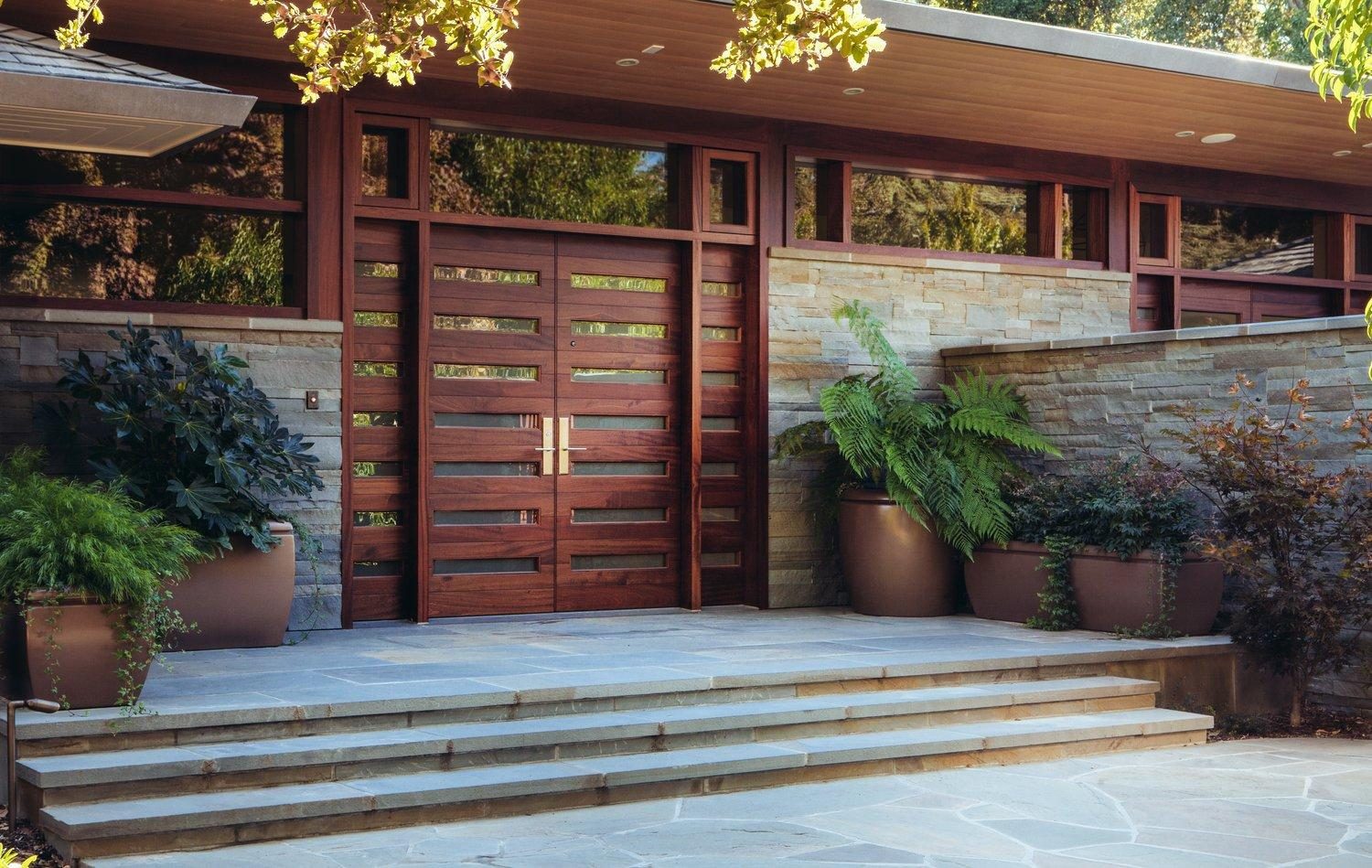 A pair of tall custom timber entry doors built by Fine Line, set in stone.