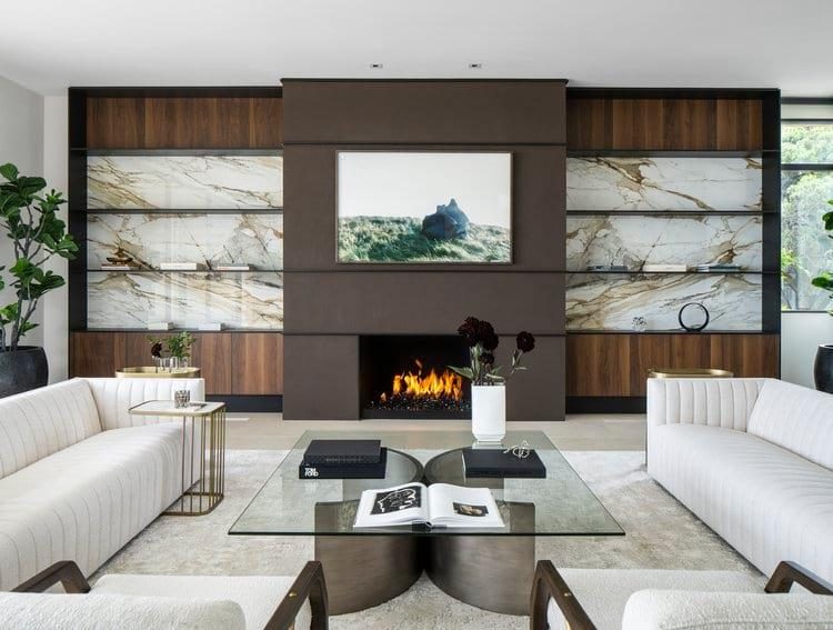 A living room fireplace wall in book-matched marble and walnut, built by Fine Line.