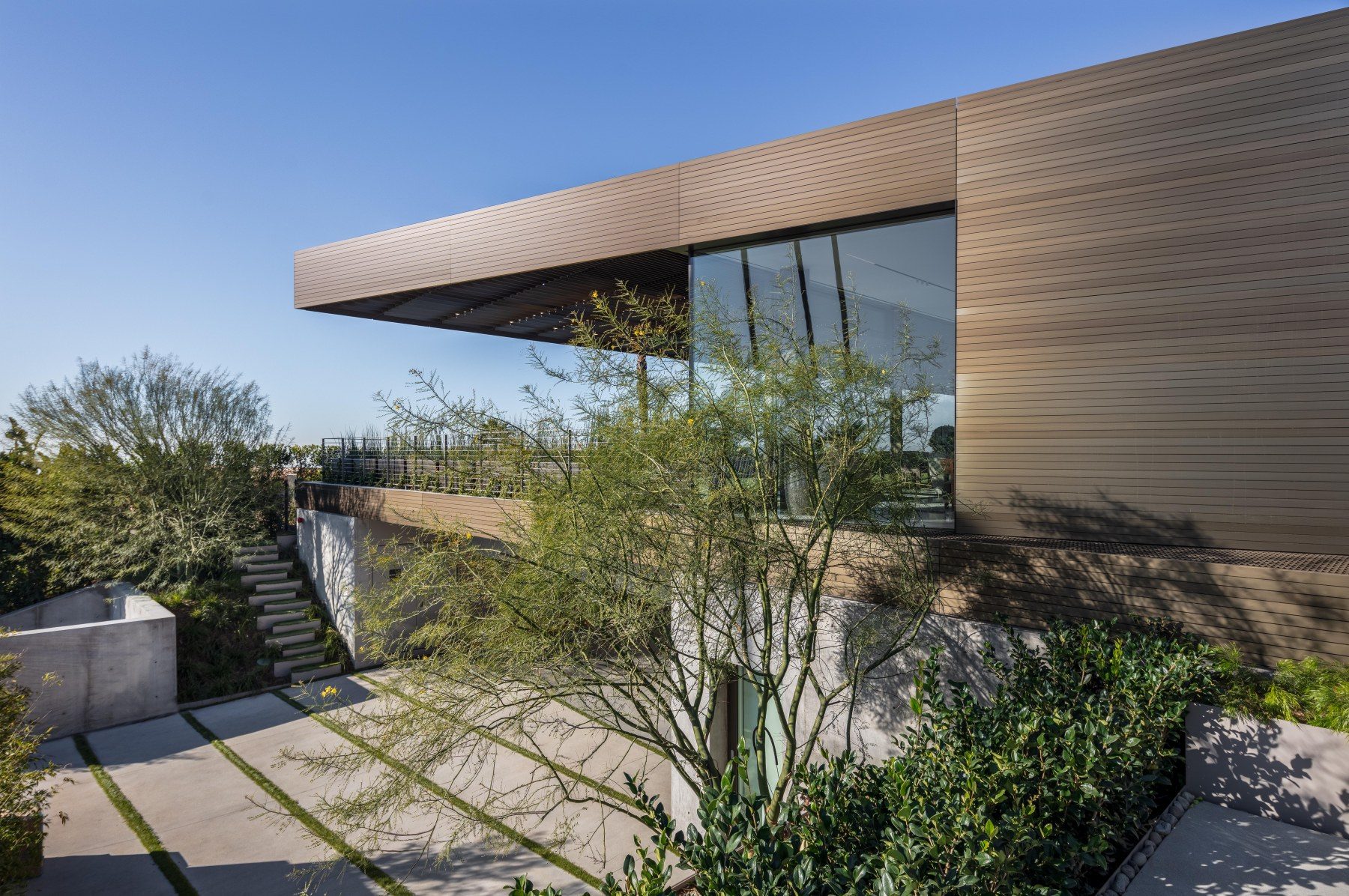 A low modern desert house with deep timber soffits, at dusk.