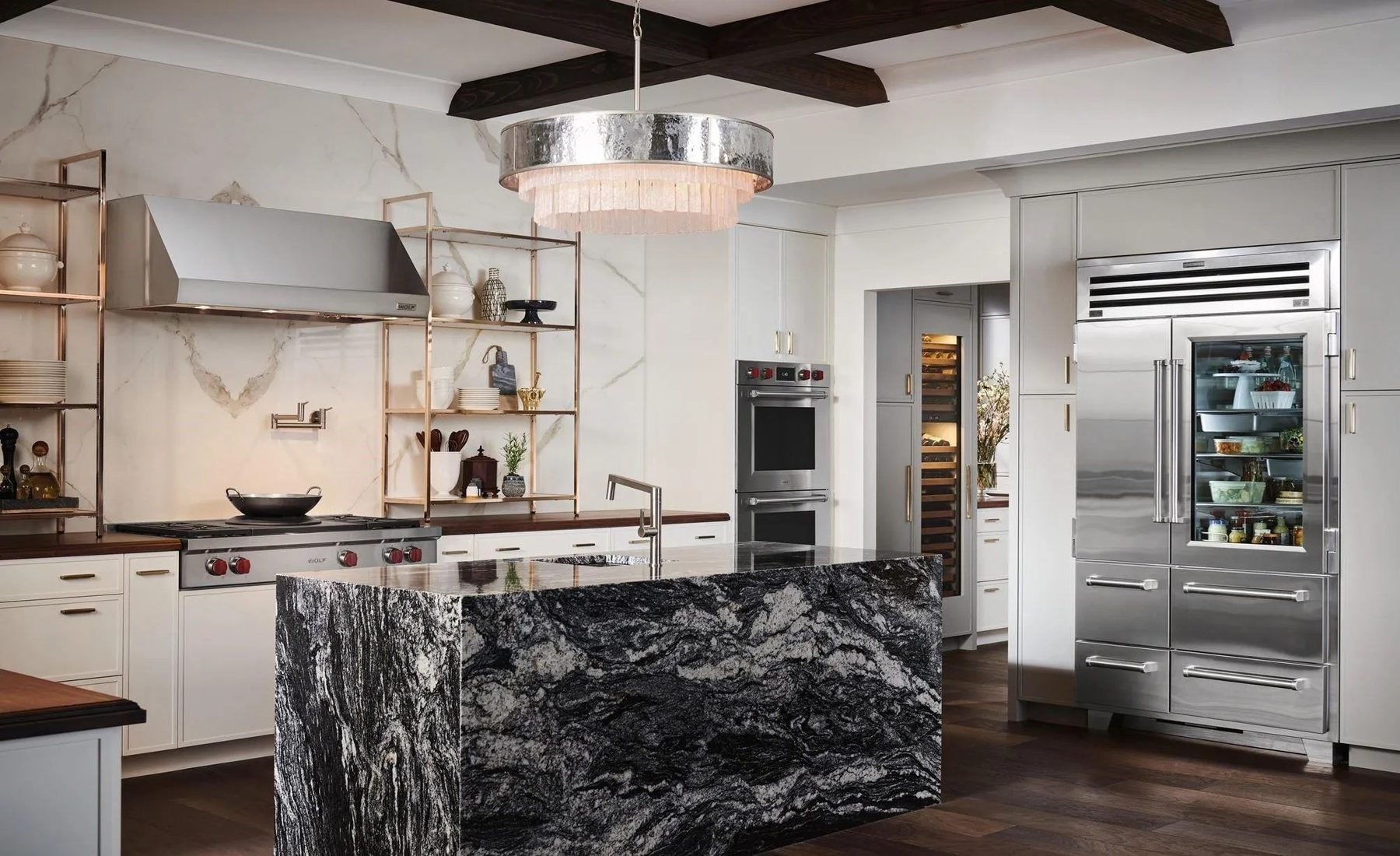 A kitchen built by Fine Line with a book-matched dark marble island, white cabinetry and integrated appliances.