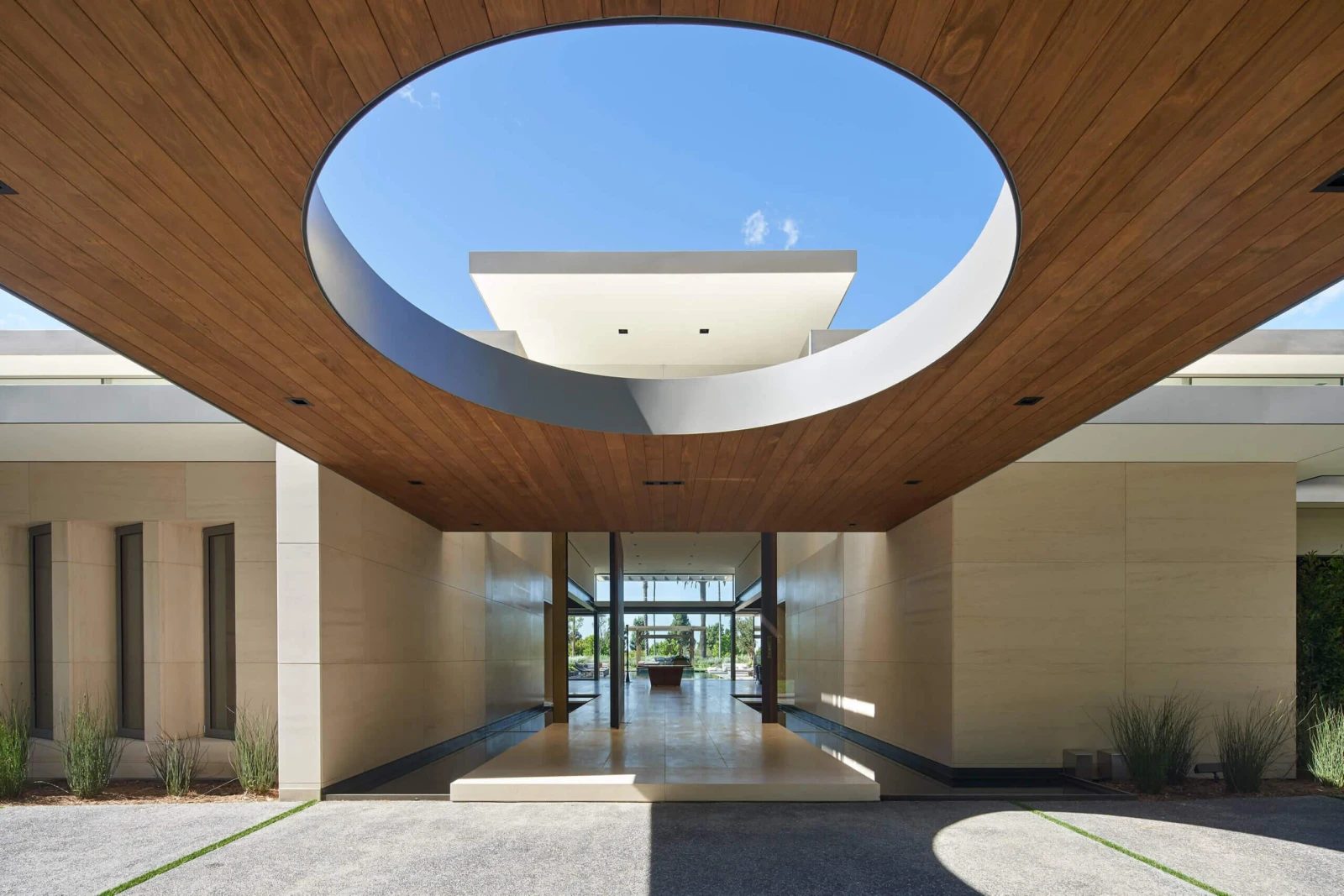 A circular skylight oculus over a timber-lined entry court, daylight, built by Fine Line.