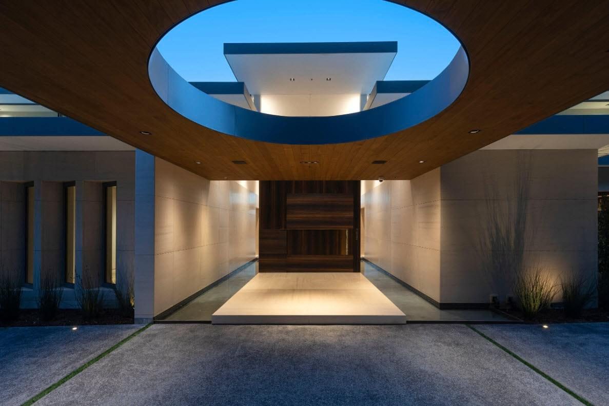 The same oculus entry at night, lit warm from within.