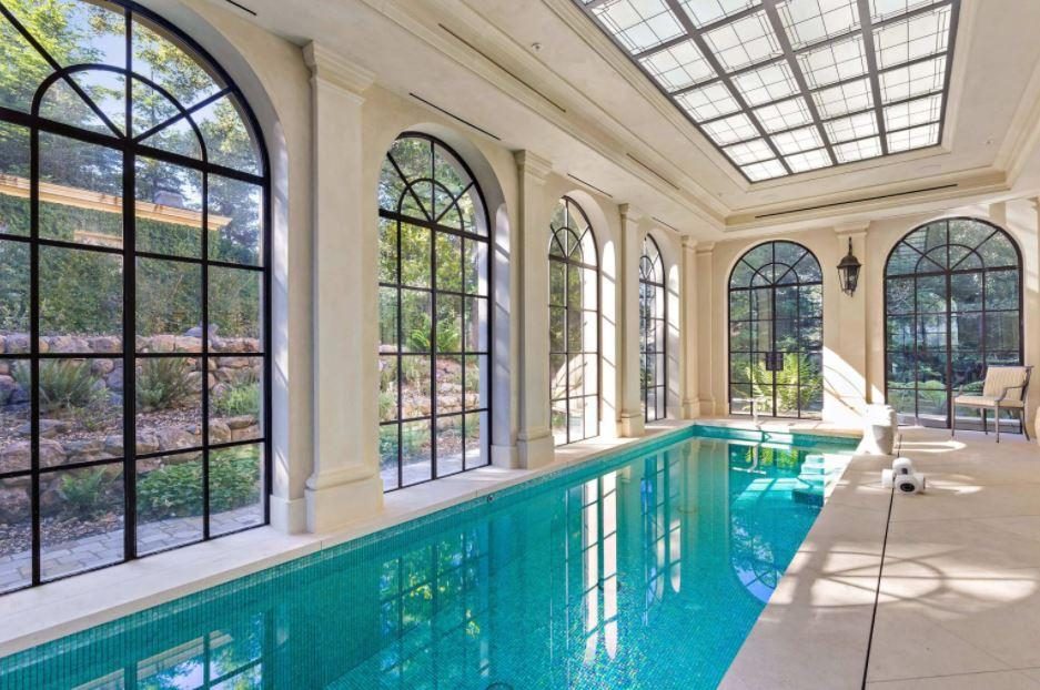 An indoor pool under an arched glazed roof with tall arched steel windows, built by Fine Line.