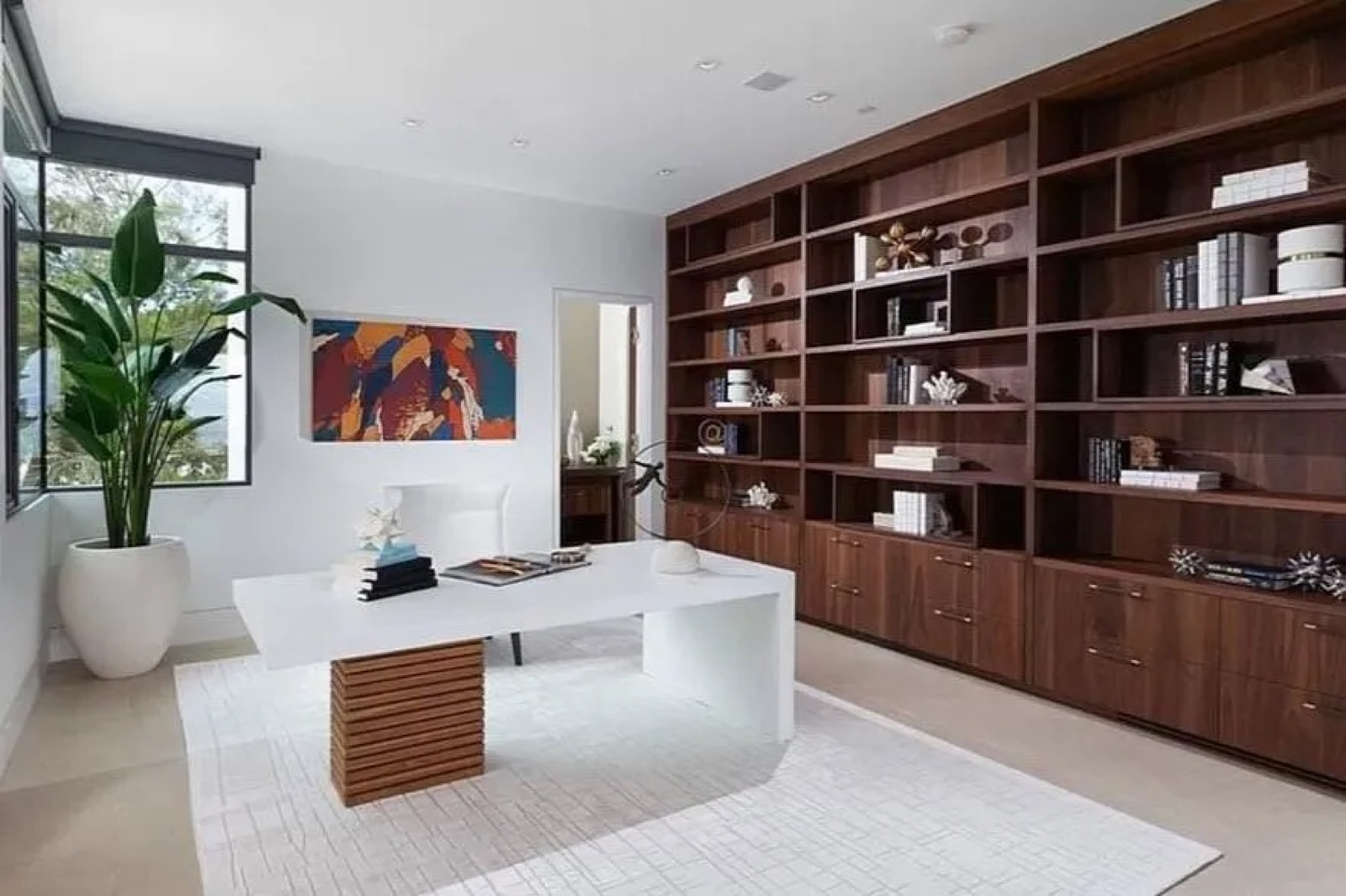 A full-height book-matched walnut library wall built by Fine Line, floor to ceiling, continuous grain.
